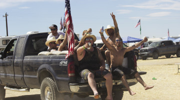 Group of men in the bed of a truck with an American flag