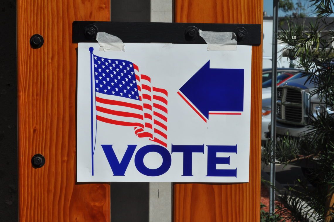 A voting sign with an American flag.