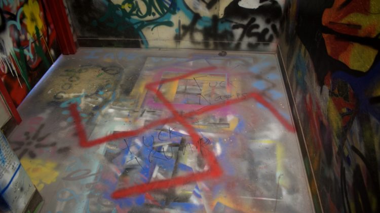 A red swastika is graffitied in Church Fine Arts graffiti stairwell on top of other graffiti