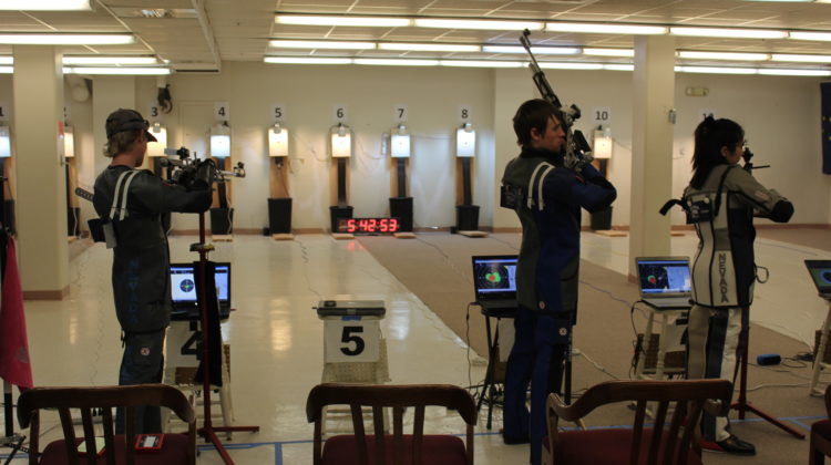 Three players on Nevada's rifle team aim at targets during practice