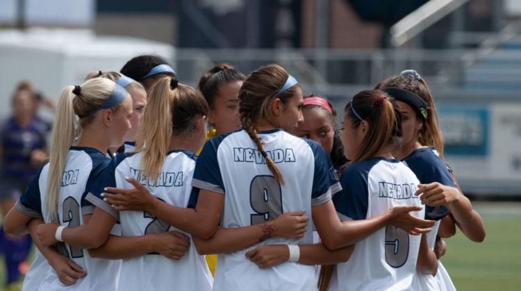 No. 9 Defender Brittany Wiehe looks to her right during a team huddle. Nevada can be seen wearing white jerseys with blue letters in the photo.