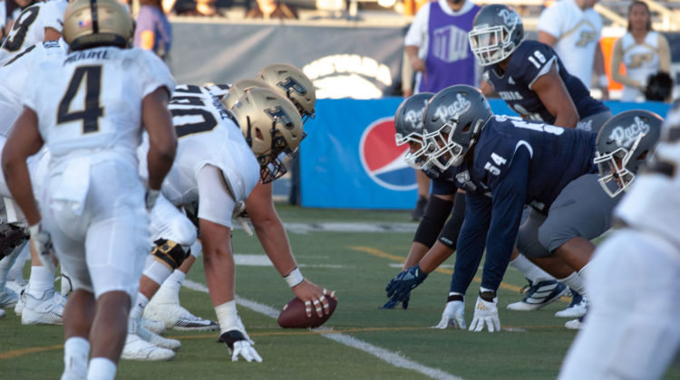 Junior defensive tackle Chris Green, wearing a blue No. 54 jersey, prepares for a play against Purdue. In the foreground of the image, Purdue's Rondale Moore runs towards the ball prior to the snapping of the football.