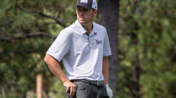 Nevada golfer Sam Harned looks to his right. Harned is wearing a white striped Pack logo and a Pack baseball cap.