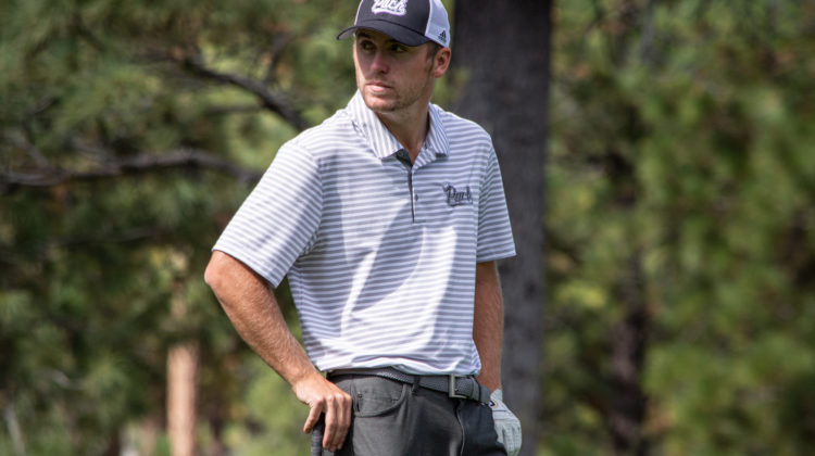 Nevada golfer Sam Harned looks to his right. Harned is wearing a white striped Pack logo and a Pack baseball cap.