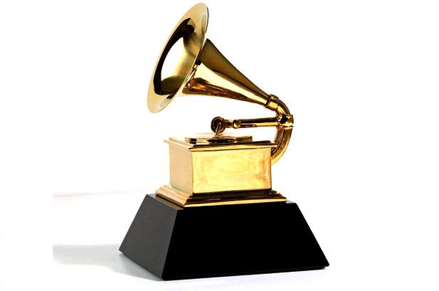 A golden Grammy award statue, which resembles a record player, sits in front of a white background.