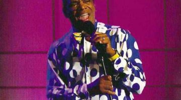 Movie poster for John Witherspoon's 2008 stand up special "You Got to Coordinate." Witherspoon is wearing a white and blue polka dotted button up shirt with a yellow bow tie. He is holding a microphone on stage.