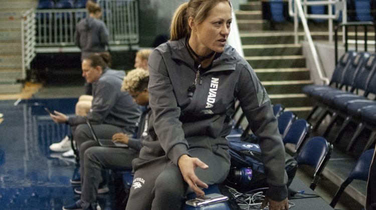 Head coach Amanda Levens sits in all grey warm up suit in Lawlor Events Center.