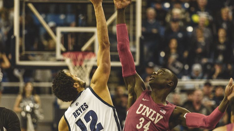 Johncarlos Reyes jumps for the tip off at Lawlor Events Center on Jan. 22 versus UNLV. Reyes is wearing an all white uniform with blue lettering.