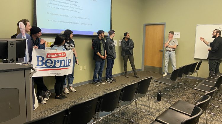 Students stand with a Bernie sign as they participate in a mock caucus.