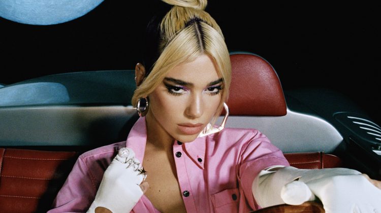 Dua Lipa—wearing a two-tone colored top knot hairstyle, a pink button-up shirt and long white gloves—is pictured with her hand on a steering wheel with the moon in the upper left corner.