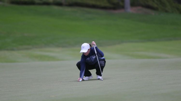 Victoria Gailey places golf ball on course.