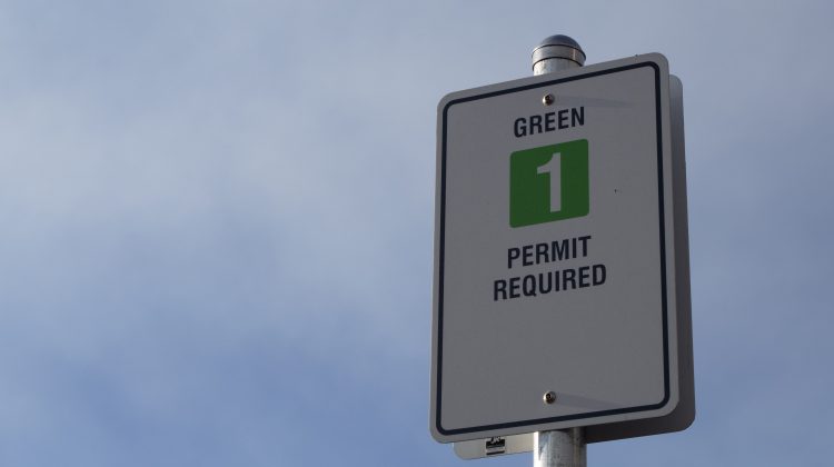 Sign for the green parking lot with sky behind it.