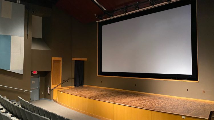 A movie room with a large screen and empty audience seats after the event.