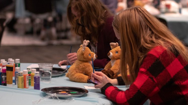Two people having fun at the winter festival, working on crafts with their crafted stuffed animals next to them.