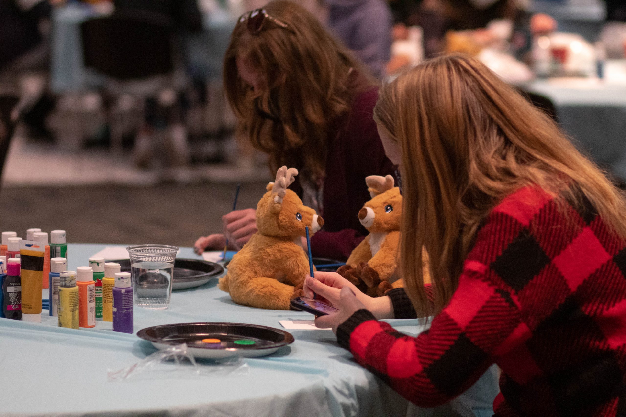 Two people having fun at the winter festival, working on crafts with their crafted stuffed animals next to them.