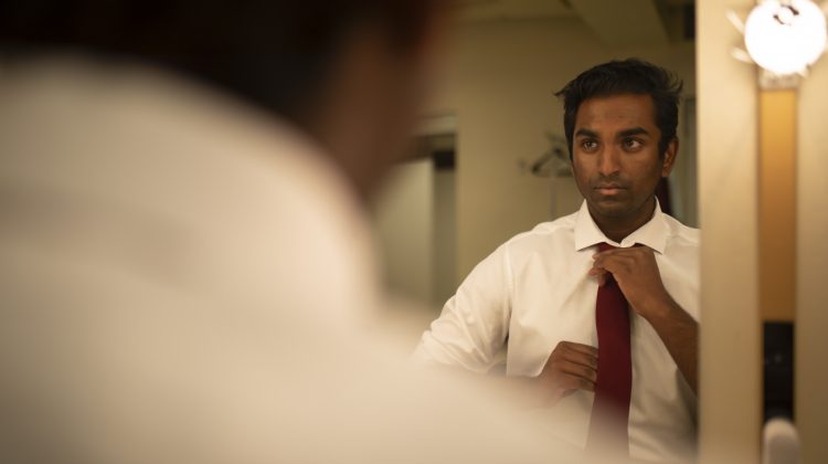 Kavin fixes his tie in his mirror backstage before the show.