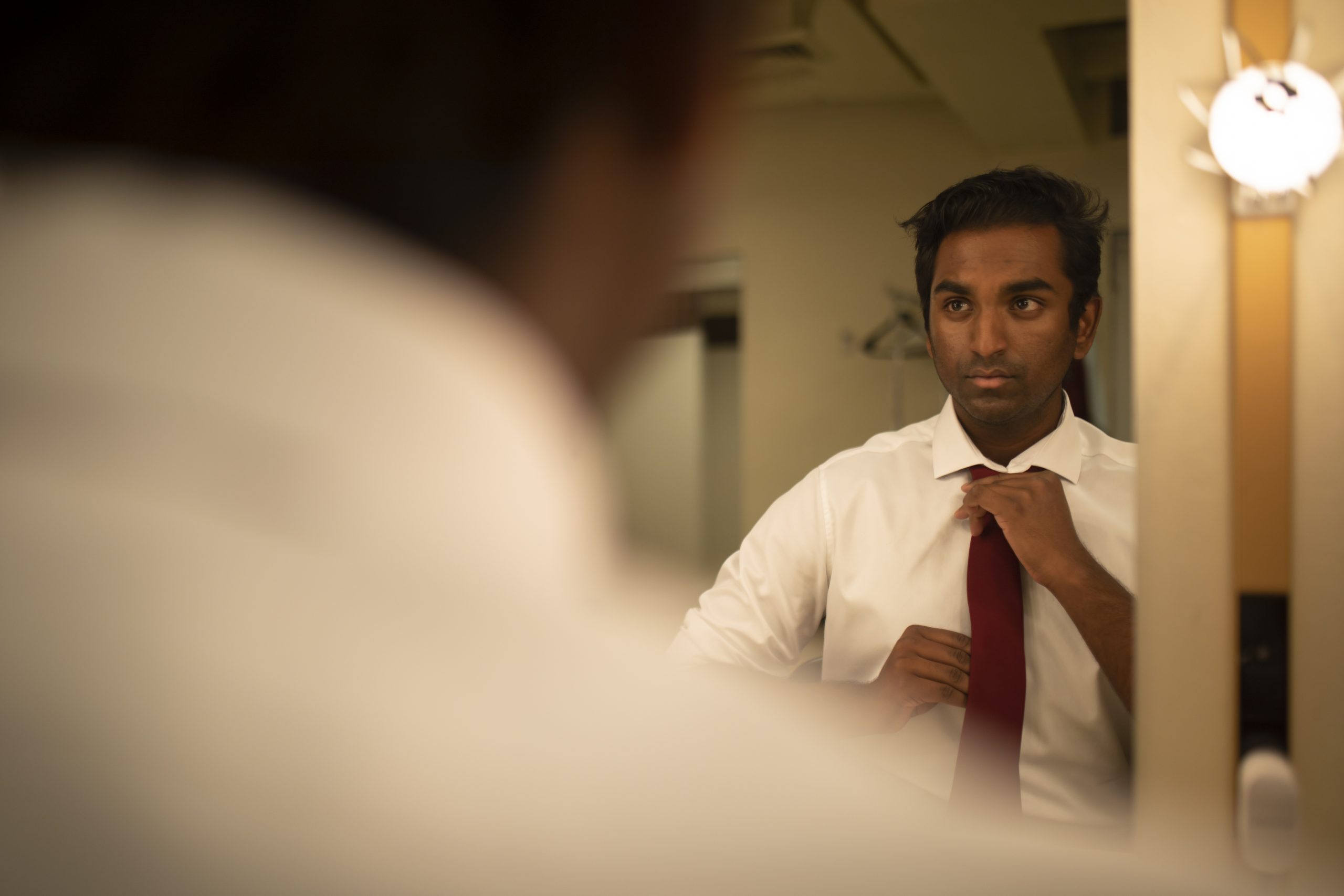 Kavin fixes his tie in his mirror backstage before the show.