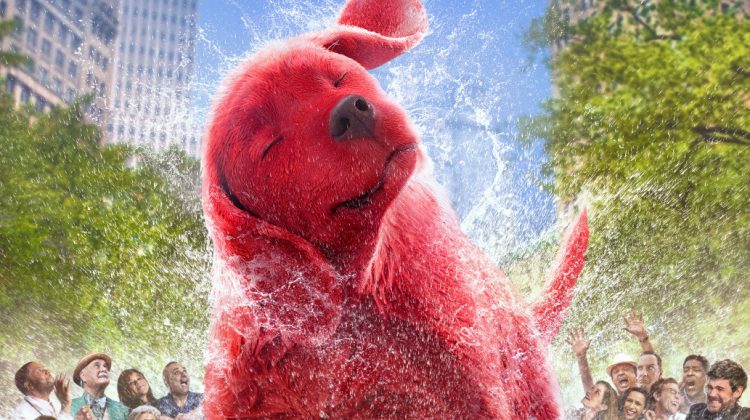A big red dog shakes the water off of him on the group of people around him in a big city. The letters of the movie "Clifford" sit at the top.