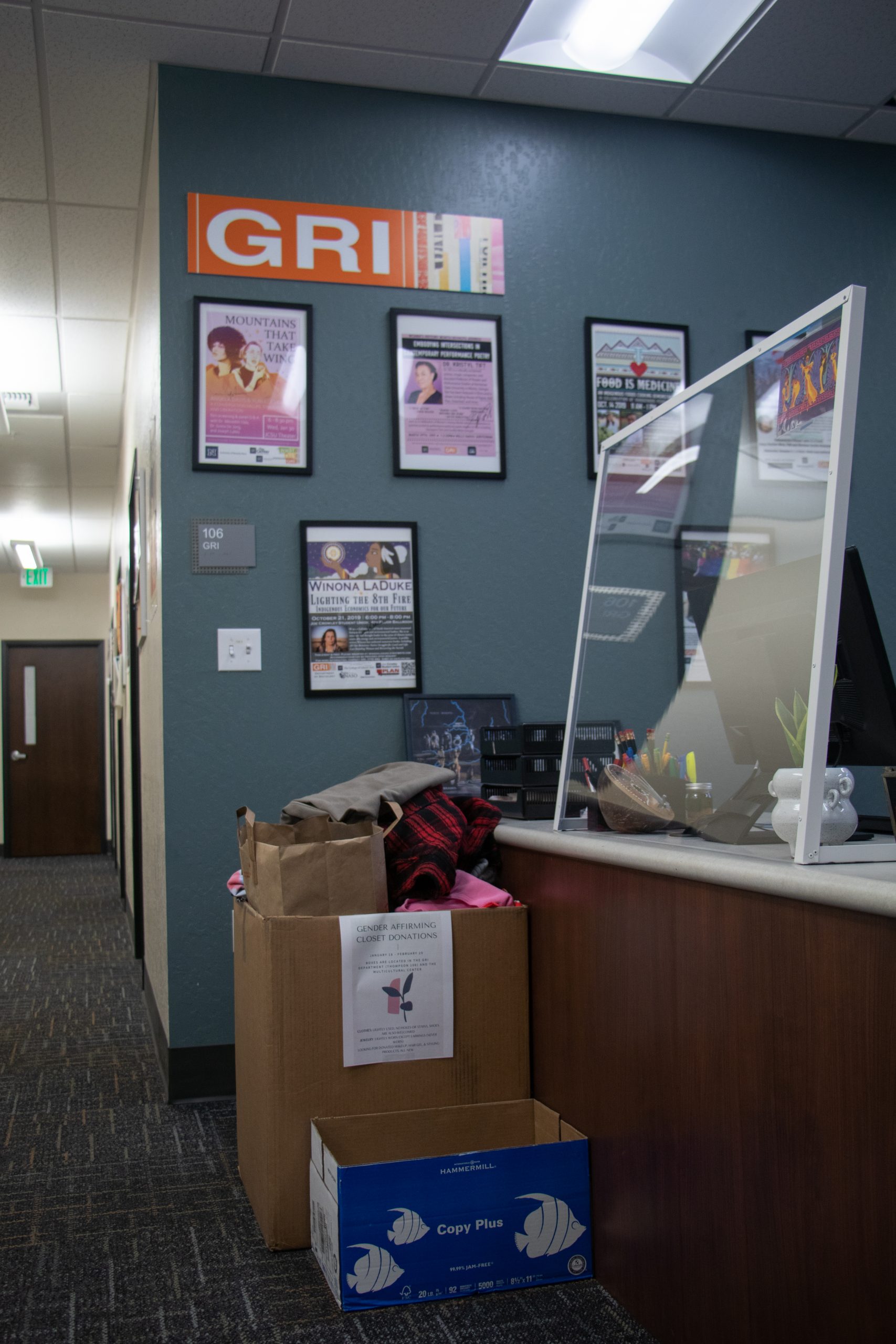 Cardboard box with a sign for clothing donations sits in front of the GRI suite desk in the Thompson Building.