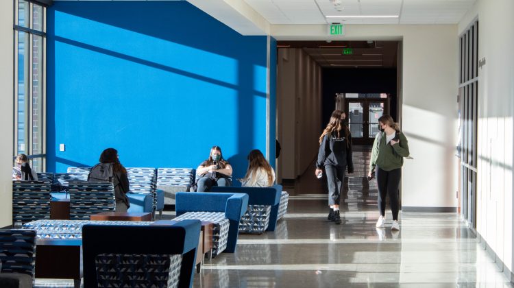 Students walk through a hallways with a blue wall behind them