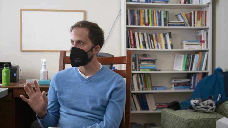 man in a blue shirt wearing a black mask is speaking