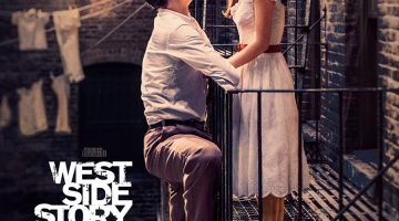 A young boy and girl stare into one another's eyes as the boy hands over a railing, confessing his love for the girl outside an apartment building.